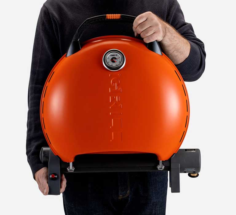 A person is holding O-Grill 600MT Portable Gas Grill